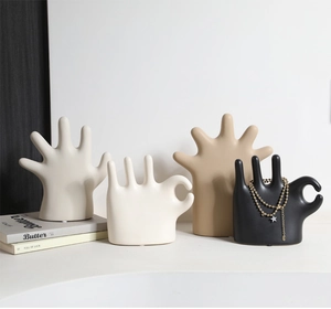 Detail view of matte ceramic hand-shaped jewelry displays in four minimalist colors