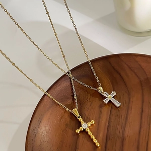 French style gold cross pendant necklace with zircon crystals on a wooden tray