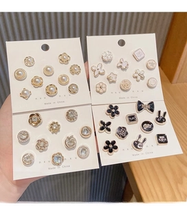 Close-up of decorative pearl, rhinestone, and enamel safety brooches on display card