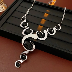 Close-up of silver geometric pendant necklace with black oval stones on display tray