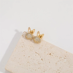 Gold rabbit stud earrings with white cubic zirconia and pink gems on a white stone base
