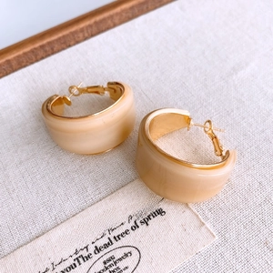 Vue détaillée des boucles d'oreilles rétro en résine crème avec bordure dorée