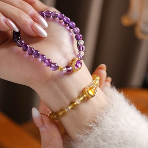 Detailed shot of yellow and purple beaded bracelets with gold heart-shaped charms