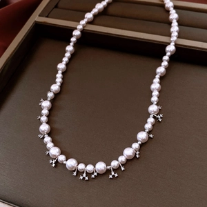 Close-up of pearl necklace with gradient sizes and starburst diamond pendants on leather