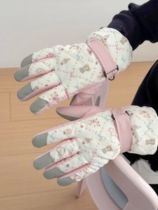 Close-up of pink quilted ski gloves featuring bear pattern and touchscreen fingertips