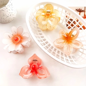 Chic hollow plumeria hair claws in pastel colors displayed in a white woven basket