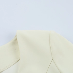 Detailed close-up of the collar and shoulder stitching on a cream two-piece skirt set