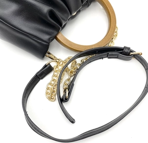 Macro shot of black pleated leather handbag with round wooden handle and gold chain strap