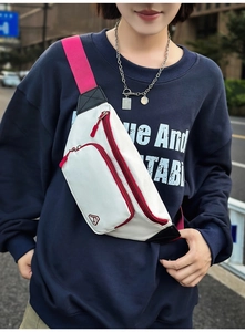 Außenaufnahme der beigen Crossbody-Brusttasche mit kräftigen pinken Reißverschlüssen