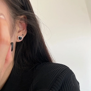 Close-up of model wearing black heart stud earrings with silver edges in minimalist style