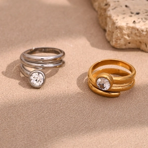 Detail of 18K gold and silver snake head rings with round white diamonds on beige stone