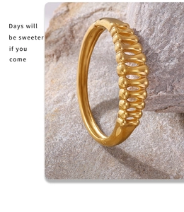 Macro shot of gold-plated herringbone hollow bangle set against a natural raw stone