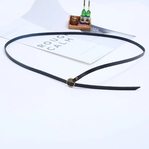 Macro shot of a slim black leather bracelet with a minimalist gold round buckle clasp