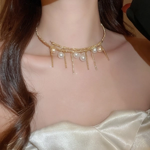 Detailed view of the layered gold pearl tassel necklace on the neck of a female model
