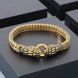 Macro shot of 18K gold plated double snake head bracelet with braided chain on jewelry box