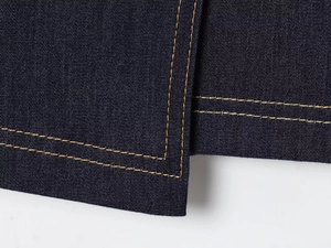 Détail du tissu denim bleu foncé avec coutures jaunes et texture sergée précise