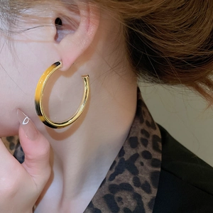 Close-up of amber resin C-shaped hoop earrings with gold trim on a female model