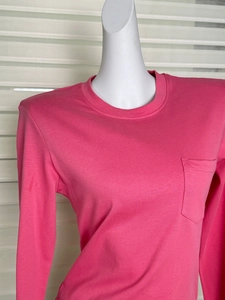 Detail view of pink cotton long sleeve shirt showing crew neck and chest pocket texture