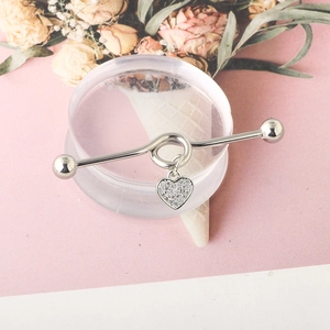 Macro shot of silver industrial barbell with a sparkling heart-shaped diamond pendant