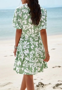 Back view of elegant green and white leaf print dress with tie waist at a sunny beach