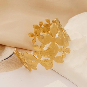 Macro shot of gold hollow flower cluster bracelet on silk fabric and stone base