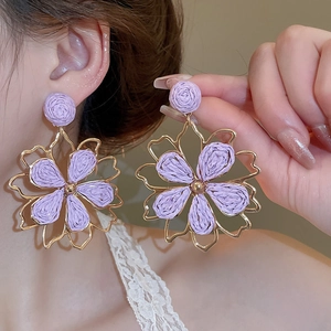 Close-up of purple woven tulle flower earrings with gold metal frame on a female model