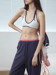 Detailed shot of white halter yoga top with navy trim and red lace waistband accents