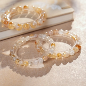 Trois bracelets en cristal jaune présentés sur un fond beige minimaliste avec lumière douce