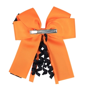 Detail of orange double-layered bow hair clip with black curly ribbons and metal clip