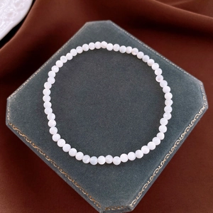 Macro shot of minimalist round faux pearl elastic bracelet on green velvet display