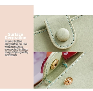 Detail of light green leather wallet showing decorative round buckle and gold snap closure