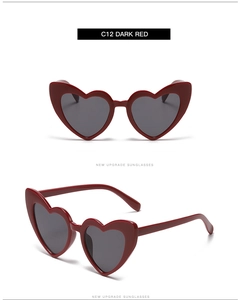 Detail view of heart-shaped dark red sunglasses with thick frames and grey lenses