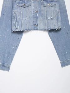 Détails d'une veste en jean bleu clair avec ornements en strass brillants et boutons en métal