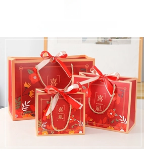 Three-piece red gift bag set with floral patterns and gold rope handles for weddings