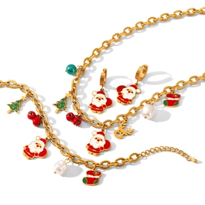 Parure de bijoux de Noël dorée avec charms Père Noël, renne et sapin sur fond blanc
