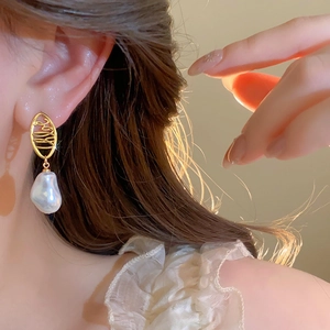 Baroque irregular pearl drop earrings on model with elegant gold-plated hollow metal detail