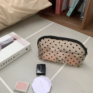 Close-up of semi-transparent mesh makeup bag with black heart patterns and zipper