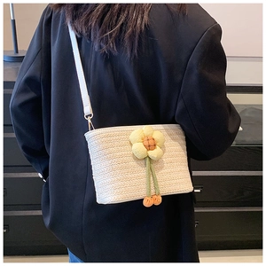 Detail of woven straw bucket bag featuring a decorative floral accent and leather strap