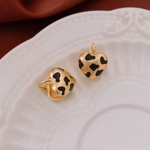 Vue détaillée de boucles d'oreilles cœur dorées avec émail tacheté noir sur plat blanc