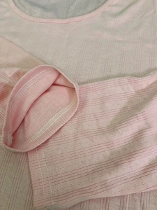Detail of soft pink pointelle knit fabric with delicate vertical ribbed texture and stitching