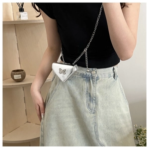 Détail du mini sac triangle argenté avec breloque papillon en métal et fine bandoulière