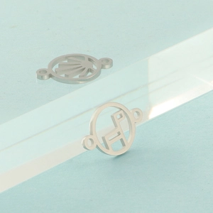 Detail of silver geometric cut-out charms and pendants with dual attachment holes