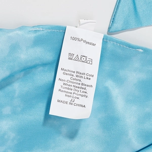 Detail showing wash care label and 100% polyester fabric texture of blue halter top