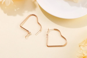 Détail macro de boucles d'oreilles cœur en or rose avec une texture ciselée précise