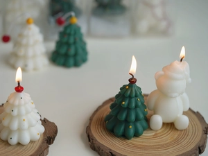 Detailed view of burning Christmas tree and bear candles on a rustic wooden base