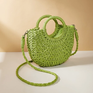 Detail of green crescent straw woven handbag with circular handles and shoulder strap