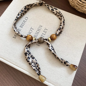 Détail du collier foulard en soie à motif léopard avec perles ambrées et anneaux dorés