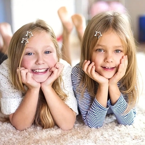Detail of silver star-shaped metal hair clips worn by young models on soft carpet