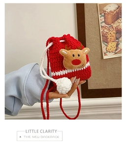 Detail of red crochet reindeer bag featuring white wave patterns and plush deer ornament