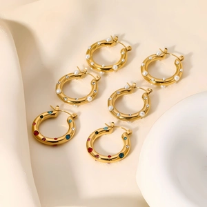 Detailed set of gold hoops with pearls, clear zircons, and colorful gemstones on a tray